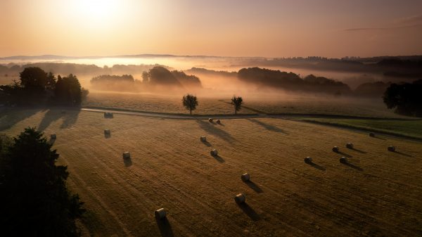 Flight over hay bales in the morning with fog in the background at sunrise in Germany, Europe